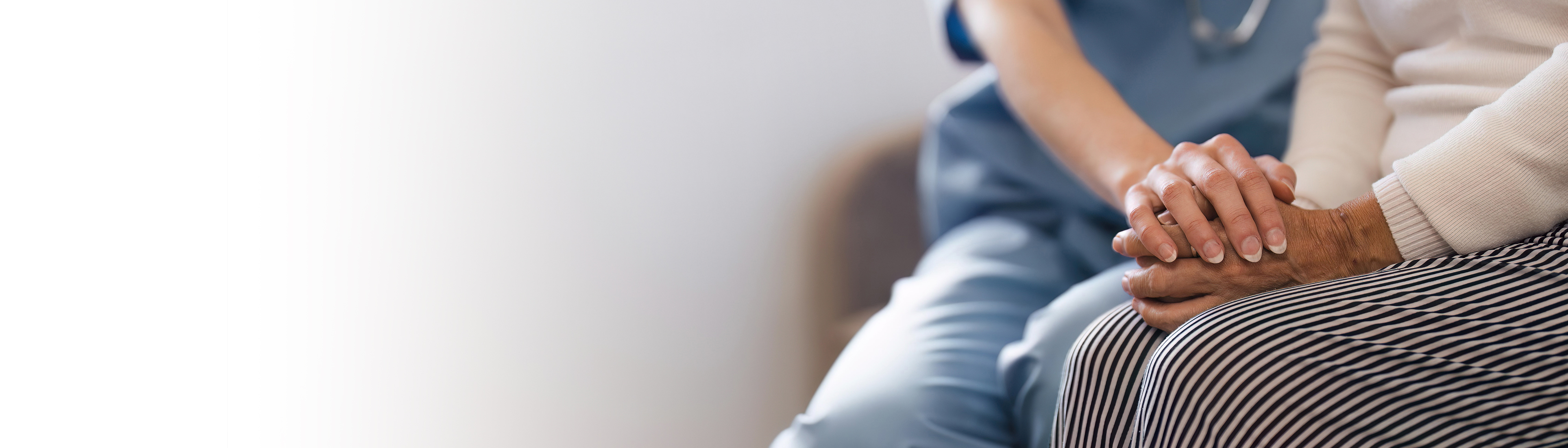 Female nurse holding the hand of an older adult woman in support